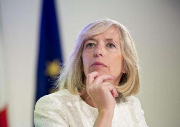 ministro giannini con una mano sul mento e dietro una bandiera dell'europa