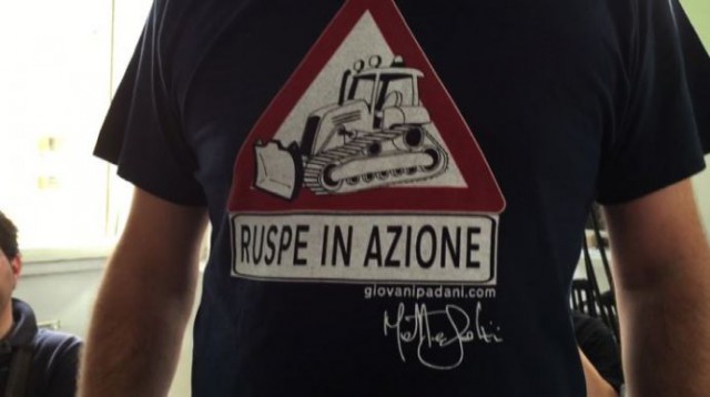 Primo piano della maglietta di Salvini. Immagine di una ruspa all'interno di un segnale di attenzione, sotto la scritta "ruspe in azione"