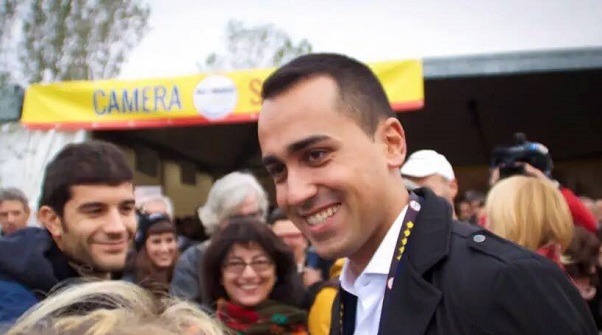 luigi di maio mentre parla ad imola con simpatizanti del movimento 5 stelle con alle sue spalle lo stand del gruppo m5s alla camera