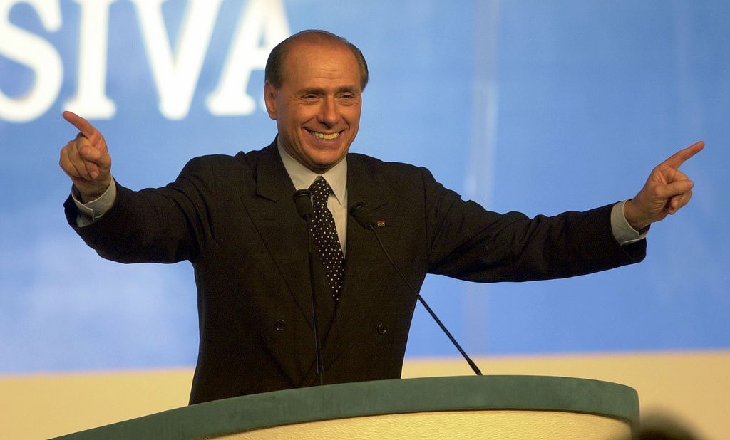 Silvio Berlusconi rinvio del referendum, sorridente al microfono
