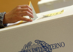 il momento del voto con elettore che inserisce la sua scheda nell'urna