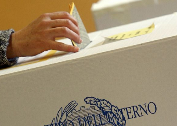 il momento del voto con elettore che inserisce la sua scheda nell'urna