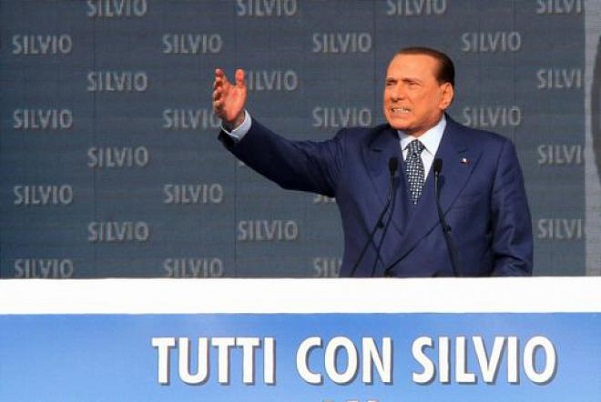 sul palco allarga le braccia silvio berlusconi in abito