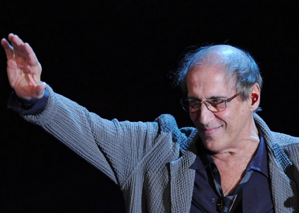 adriano celentano saluta pubblico durante uno spettacolo alzano la mano destra