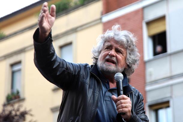 grillo che parla al microfono con la mano alzata