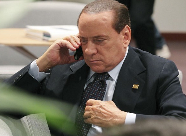 berlusconi al telefono con braccio poggiato su automobile