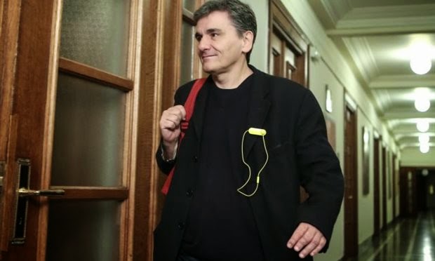 euclid tsakalotos in piedi mentre cammina sorridendo e con uno zaino in spalla