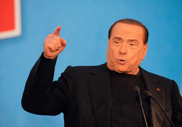 berlusconi con il braccio destro in alto e l'indice puntato