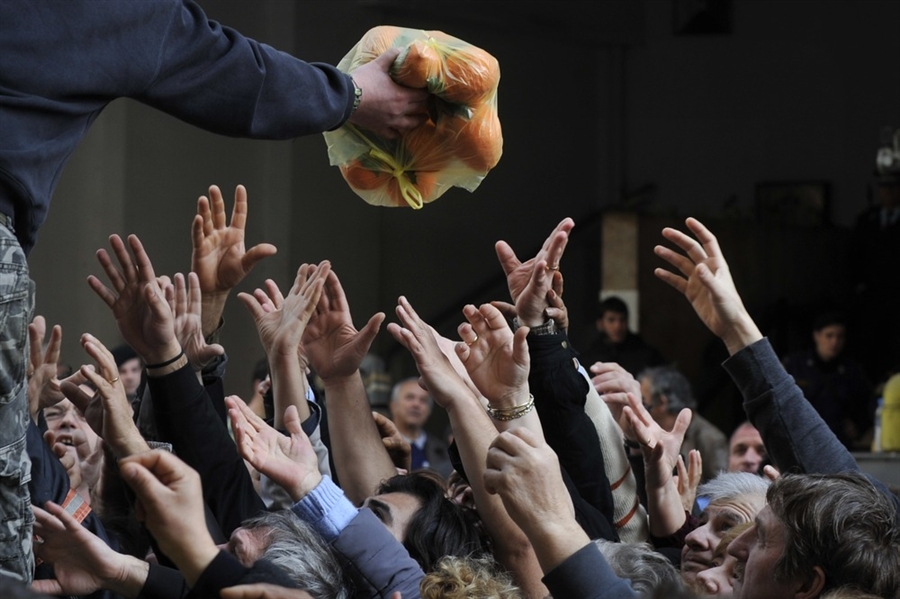 Persone che cercano di recuperare frutta e verdura distribuiti gratuitamente dagli agricoltori durante una protesta al di fuori del ministero dell'agricoltura, Atene, 6 febbraio 2013.