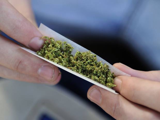 immagine di marijuana dentro una cartina con mani che la tengono tesa