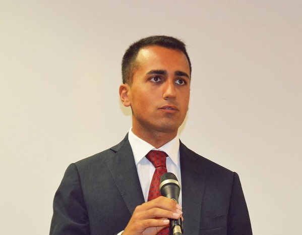 sondaggi m5s, di maio, movimento 5 stelle, il vicepresidente della camera con microfono in mano camicia bianca e cravatta rossa e sfondo chiaro