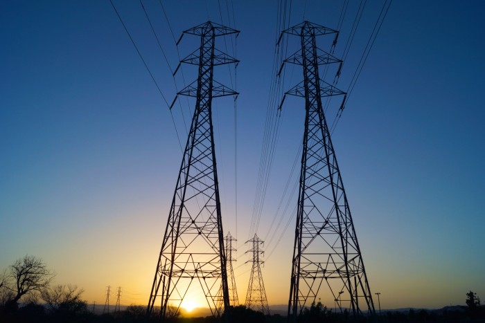 Il sole tramonta dietro a due linee di alimentazione per l'energia elettrica in acciaio in California.