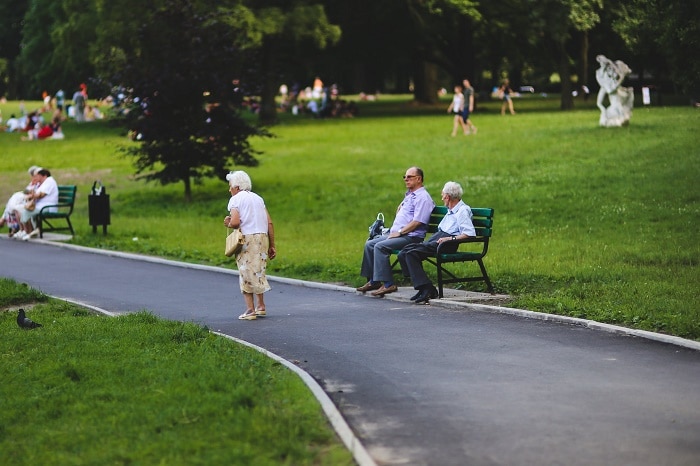 All'interno di un giardino pensionati seduti alle panchine e altri a passeggio