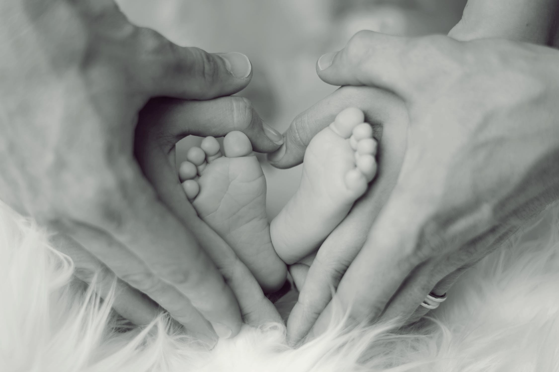 Foto in bianco e nero con piedi di un neonato e mani di un adulto