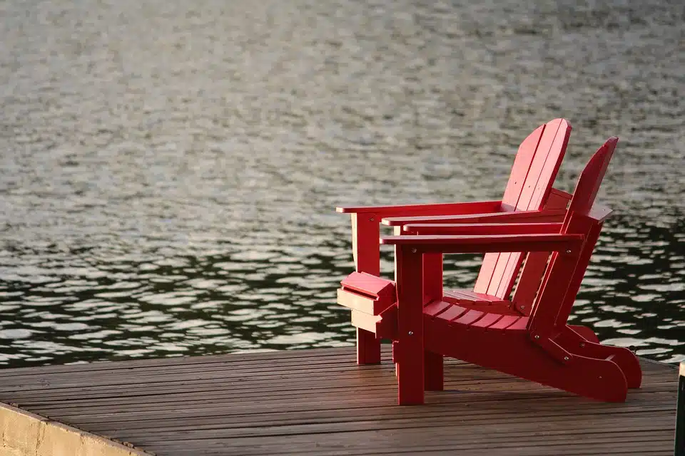 Due sedie rosse su un pontile a ridosso del lago