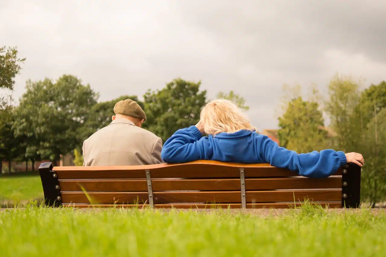Coppia di persone anziane di spalle sedute su una panchina