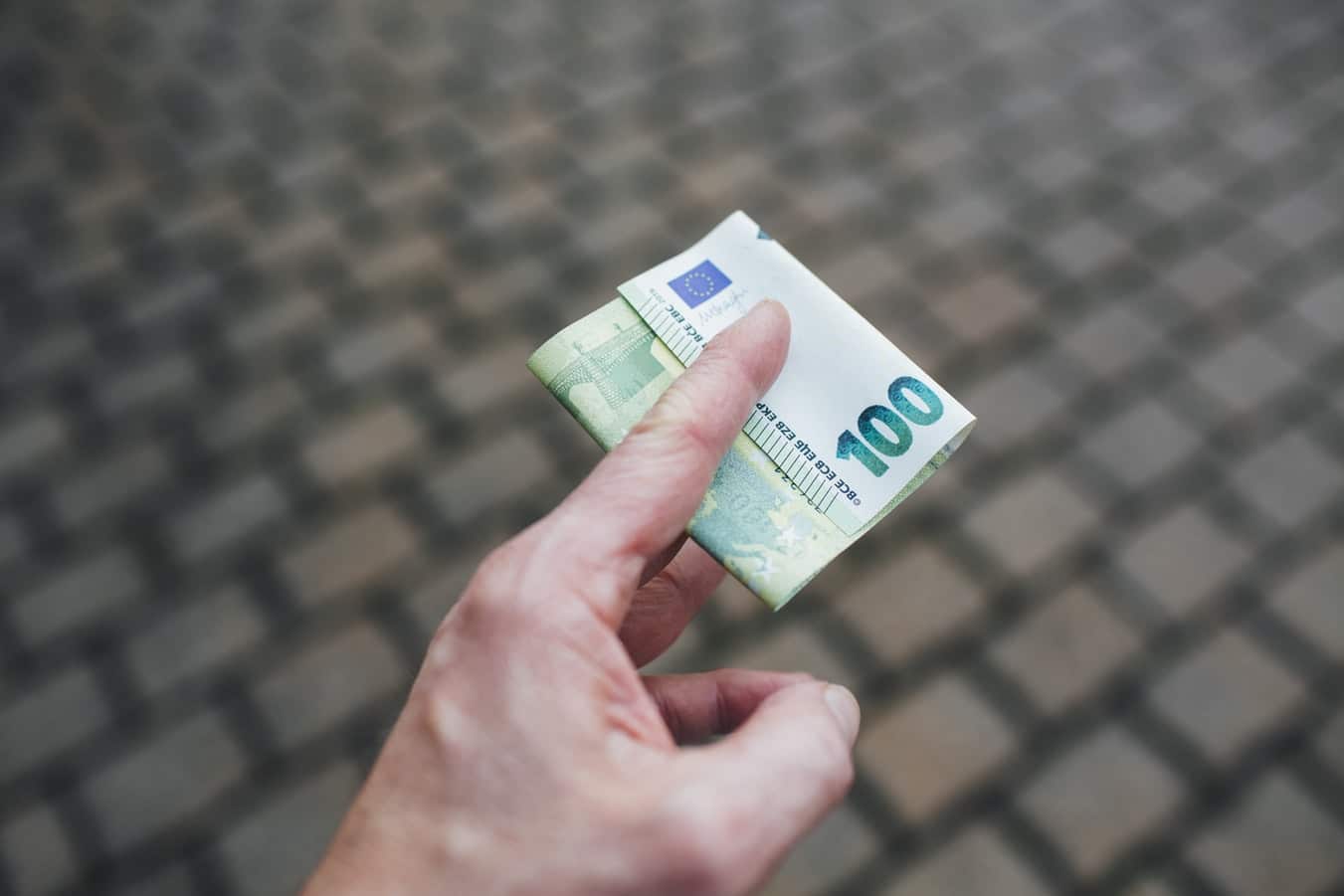 mano con in mano una banconota da 100 euro