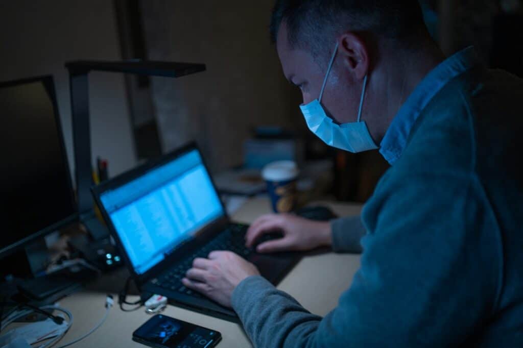 Uomo al computer con la mascherina protettiva