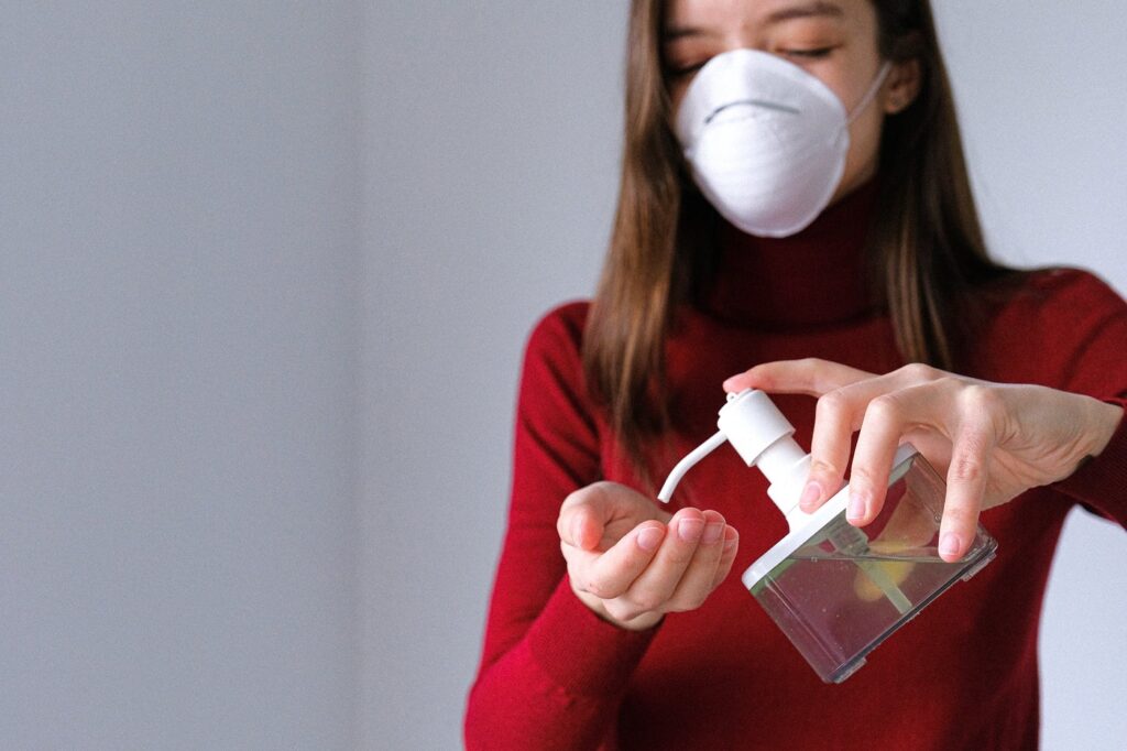 Ragazza con mascherina mentre si deterge le mani