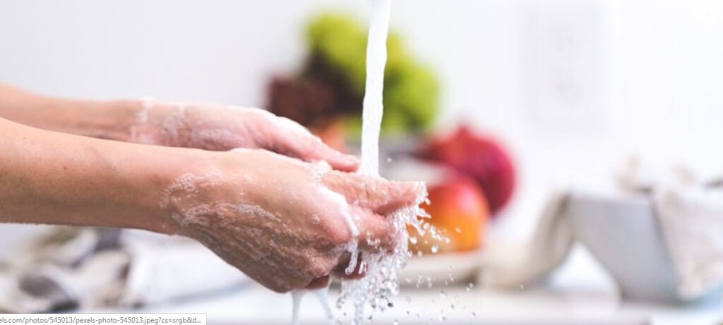 Mani di donna durante un lavaggio sotto il rubinetto con l'acqua che scorre