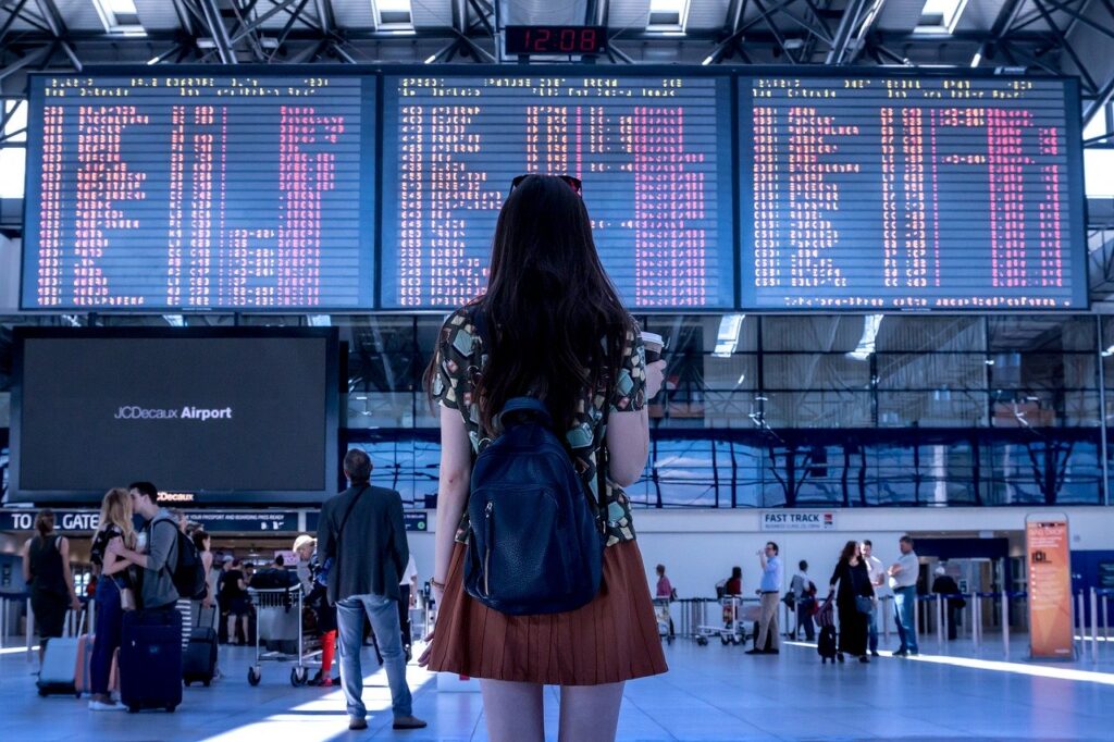 turista di fronte a uno schermo con voli cancellati