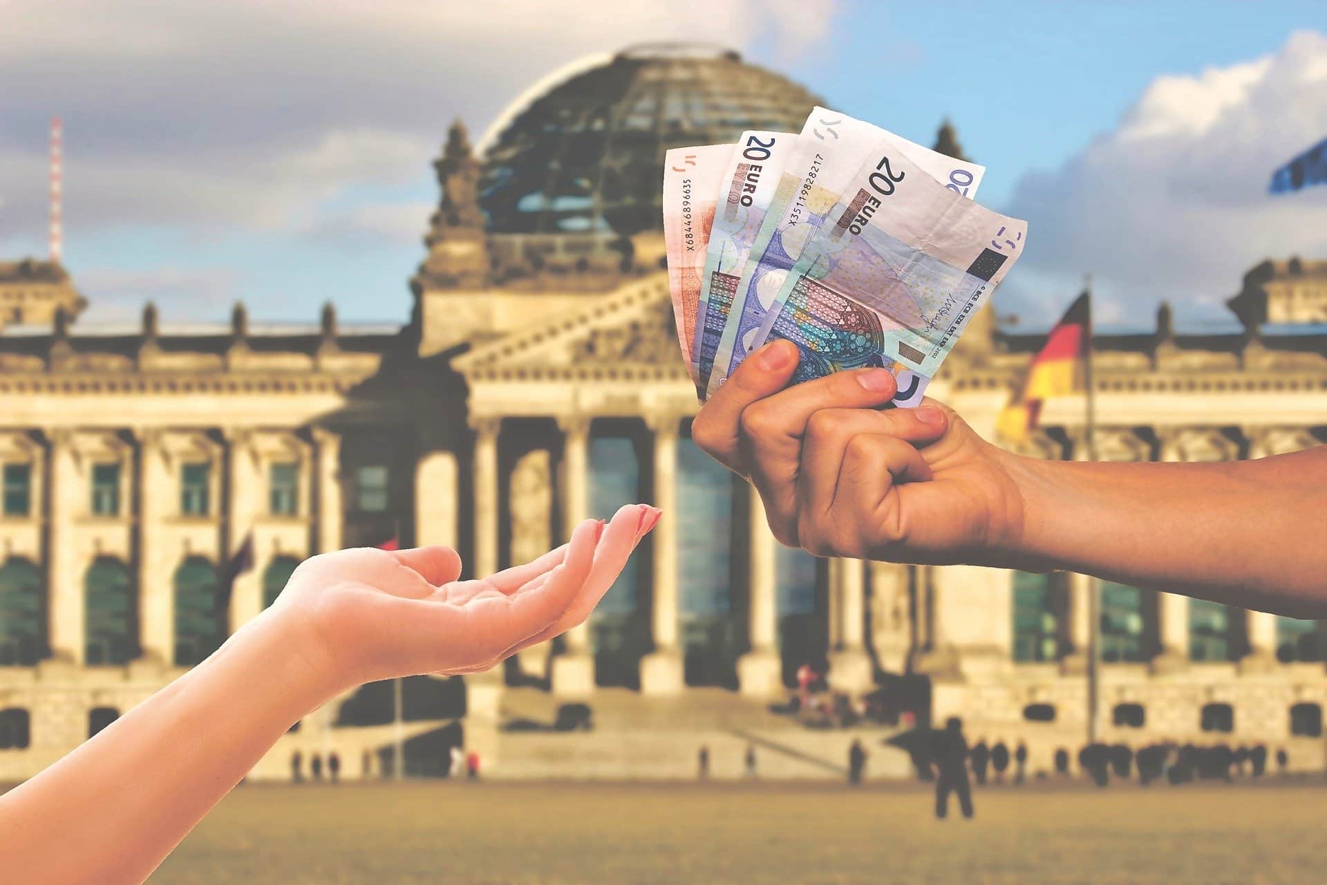 consegna a mano di banconote di euro con lo sfondo di Berlino