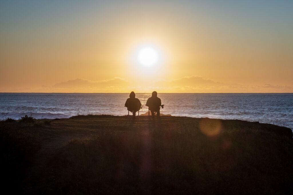 Due persone sedute ritratte di spalle e di fronte al sole