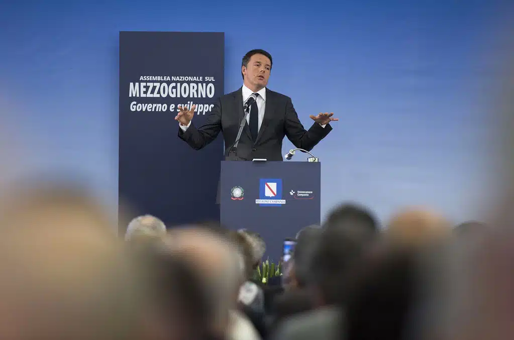 Matteo Renzi durante un evento pubblico in piedi e con le braccia allargate