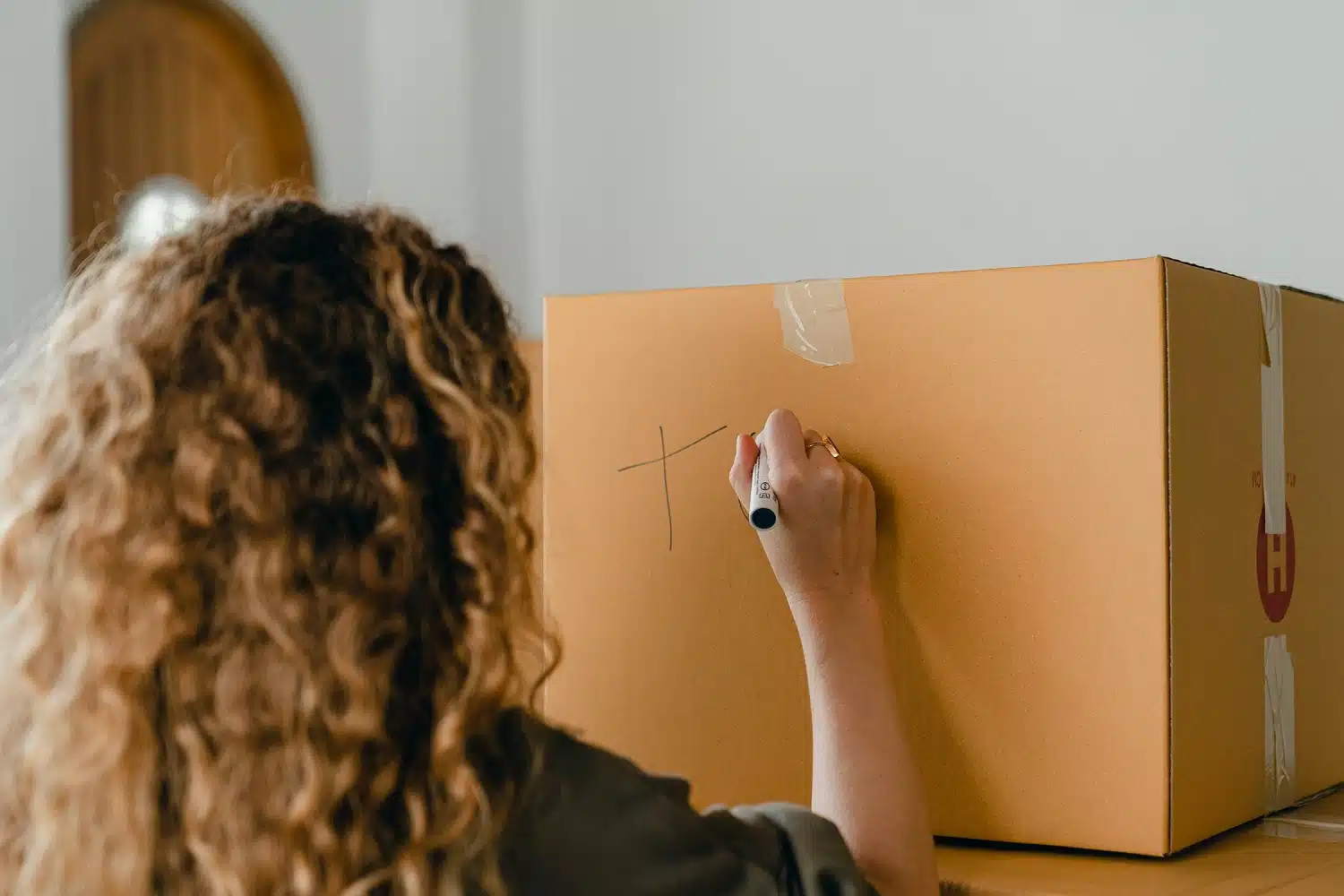 Donna riccia di spalle con pennarello mentre scrive su un cartone